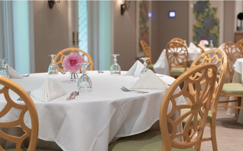 A round table set with crystal, silver, and a single pink rose